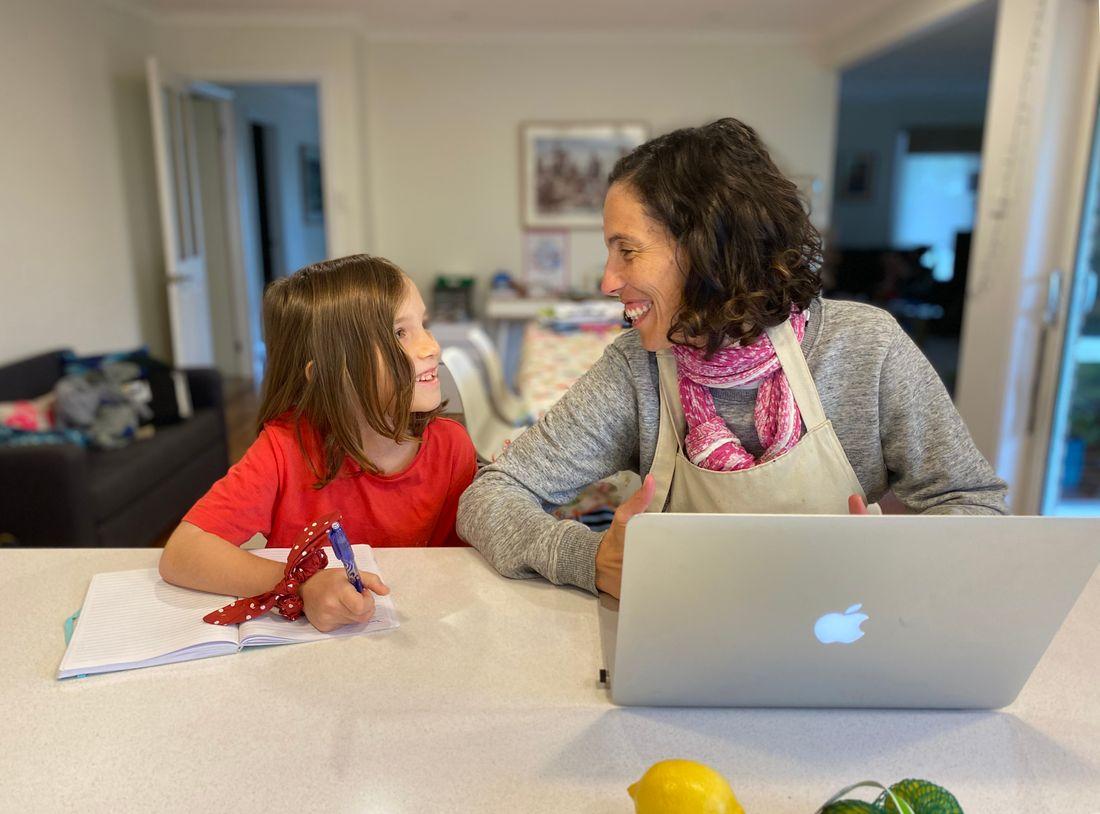 A mother and daughter learning together at the kitchen table